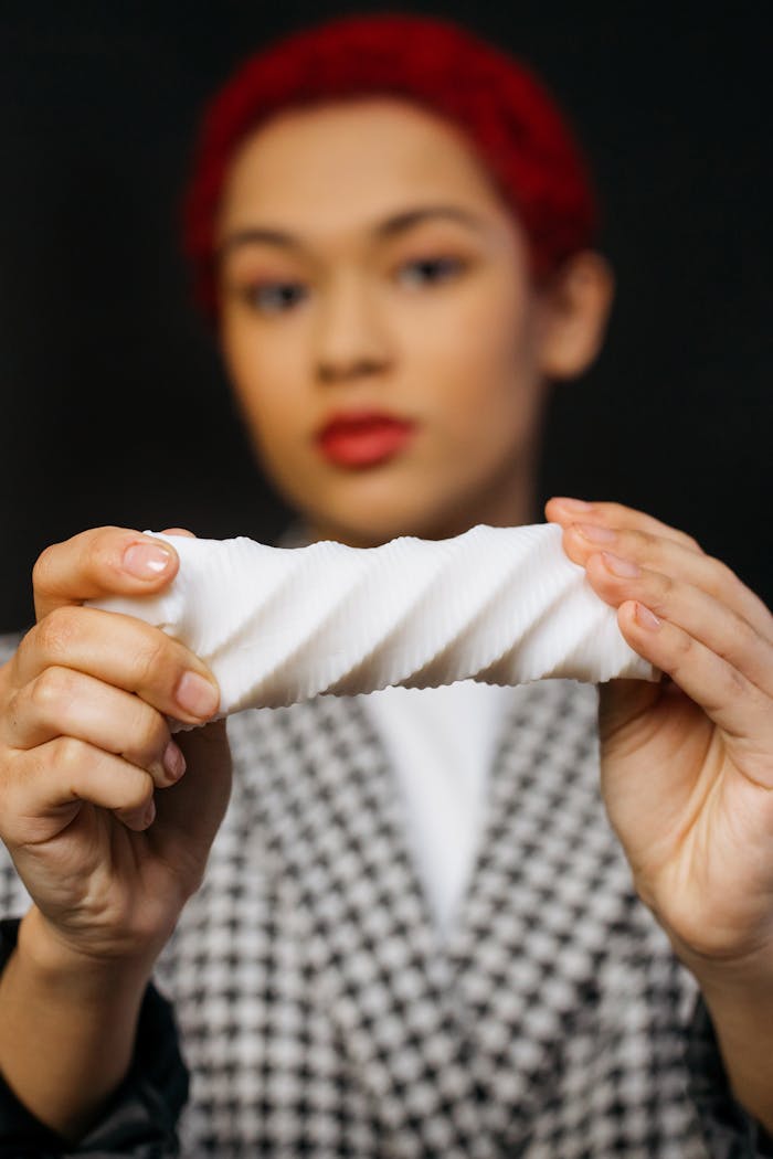Close-up of a person holding a 3D printed abstract object, blurred background.